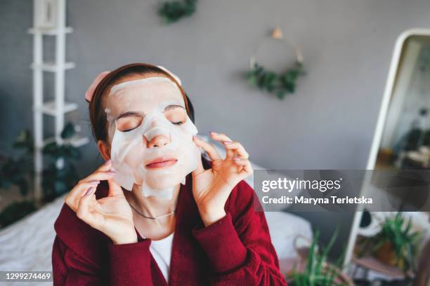 the girl put on a cosmetic cloth face mask. - cloth mask stock pictures, royalty-free photos & images