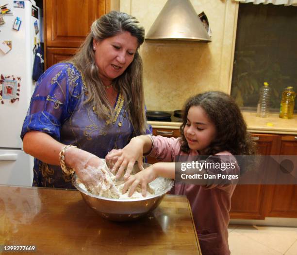 View of a woman and an eight-year-old girl as they kneed dough for Mofletta pancakes in a home kitchen, Mevaseret Zion, Israel, April 26, 2008. The...