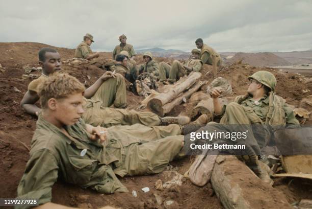 United States Marines protect themselves from Communist artillery fire by taking cover in a foxhole as US troops were completing the evacuation of...