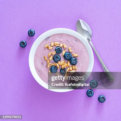 Yogurt with berries and cereal on purple colored background. Overhead view Yogurt with berries and cereal on purple colored background. Overhead view
