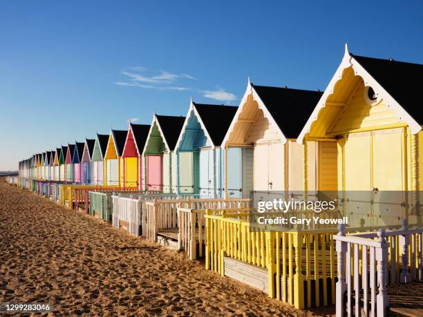 row of multi coloured beach huts - cabine de plage photos et images de collection