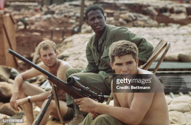 United States Marines sitting on sandbags with one holding his rifle at Khe Sanh Combat Base, a United States Marine Corps outpost south of the...