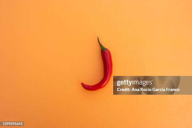 a red chili pepper on the center of an orange background. top view - chili farm stock pictures, royalty-free photos & images