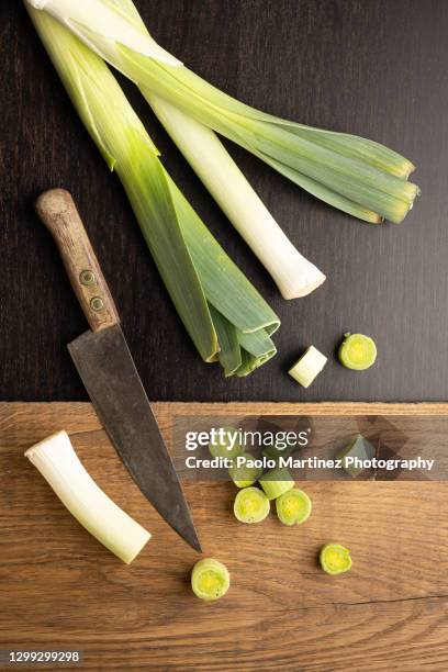 leeks and knife on wooden black background - leek stock pictures, royalty-free photos & images