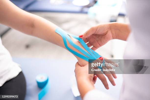 female physiotherapist is examining to her patient. - kinesiotape stock pictures, royalty-free photos & images