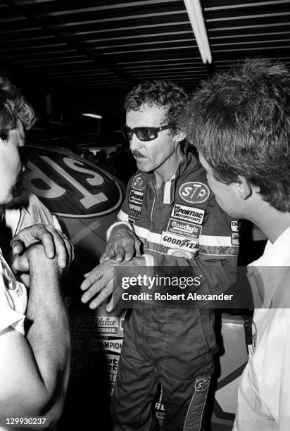 Richard Petty, driver of the STP Pontiac, talks with his racing crew members in the Daytona International Speedway garage during a practice session...