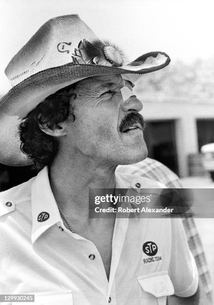 Richard Petty, driver of the STP Pontiac, walks through the Daytona International Speedway garage area after qualifying for the 1987 Firecracker 400...