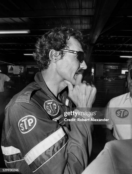 Richard Petty, driver of the STP Pontiac, talks with his racing crew members in the Daytona International Speedway garage during a practice session...