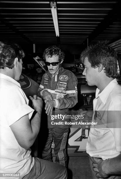 Richard Petty, driver of the STP Pontiac, talks with his racing crew members in the Daytona International Speedway garage during a practice session...