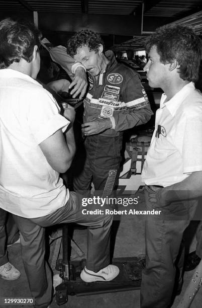 Richard Petty, driver of the STP Pontiac, talks with his racing crew members in the Daytona International Speedway garage during a practice session...