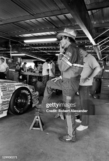 Richard Petty, driver of the STP Pontiac, pauses in the Daytona International Speedway garage prior to qualifying for the 1983 Firecracker 400 on...