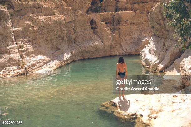 young woman relaxes by clear water pool in the morning - desert oasis stock pictures, royalty-free photos & images