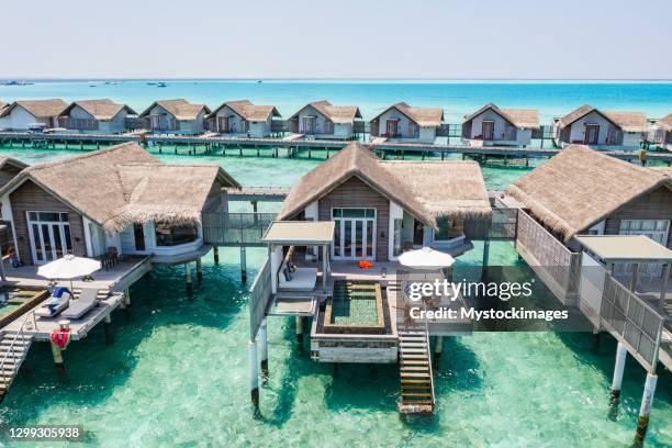 drohnenansicht der luxusbungalows auf den malediven, mann auf der treppe arme ausgestreckt - bungalow stock-fotos und bilder