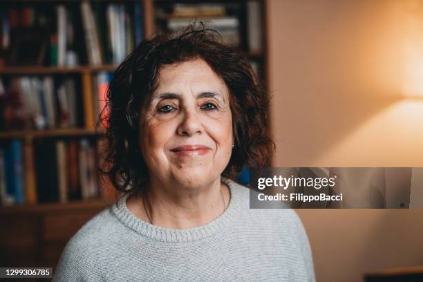 portrait of a caucasian woman with a bookcase in the background - female authors stock pictures, royalty-free photos & images