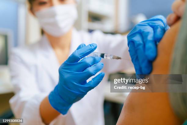 hombre adulto de la tercera edad vacunarse en el consultorio del médico - vaccine fotografías e imágenes de stock