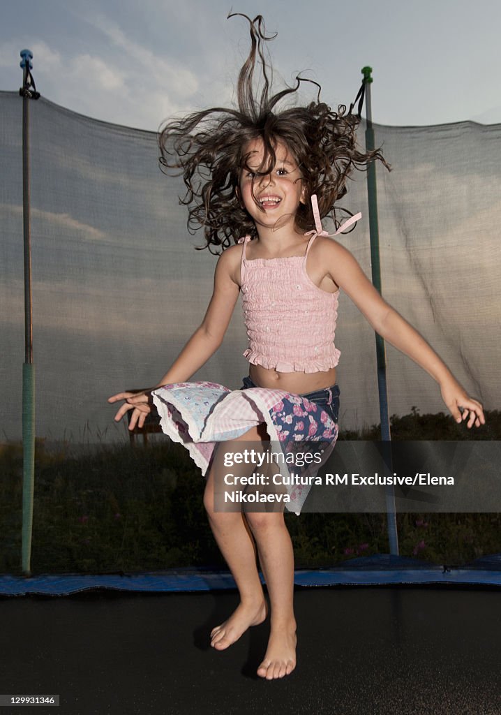 Girl jumping on trampoline outdoors