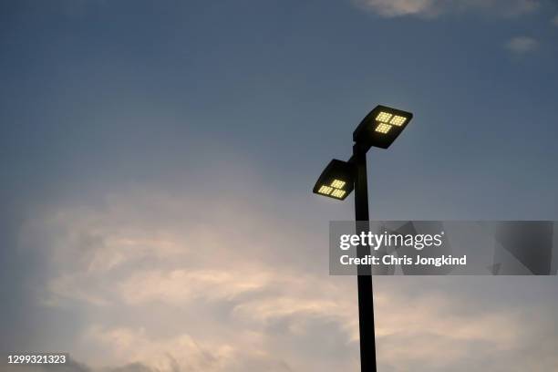 street light lit up against sunset - led street lighting stock-fotos und bilder