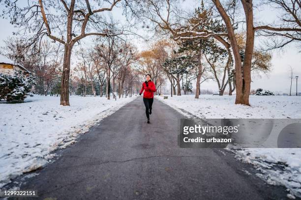 femme exécutant le jour d’hiver en stationnement - jogging winter photos et images de collection