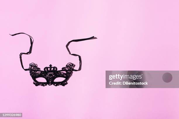 a black lace venetian carnival mask / eye mask with black ribbons on a pink background. carnival concept - black lace background stock pictures, royalty-free photos & images