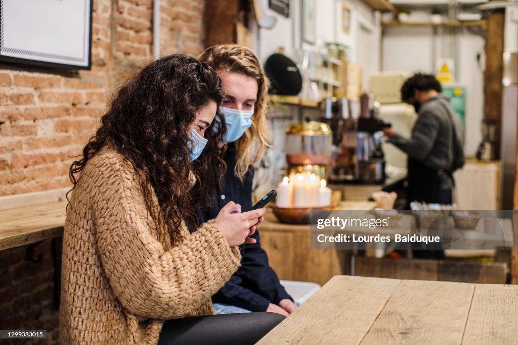 Happy couple in love with face mask in coffe shop