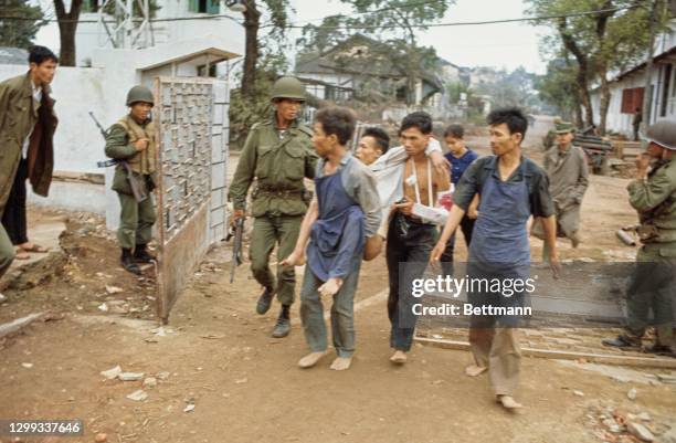 Vietnamese officer speaks to a group of men carrying an injured Vietnamese man through the streets where Allied and Communist forces continue to...