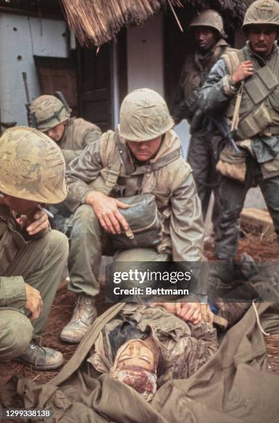 United States Marines tending to a wounded North Vietnamese soldier who lies on the ground after being found below an outer Citadel Wall in Hue,...