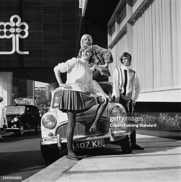 Models wearing driving outfits next to a Mini Cooper S at the Royal Garden Hotel on Kensington High Street, London, UK, 14th September 1966. From...