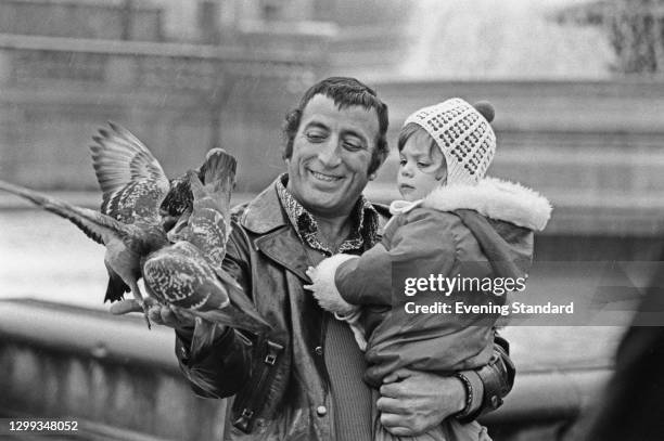 American singer Tony Bennett feeding the pigeons with his daughter Joanna, UK, 14th January 1972.