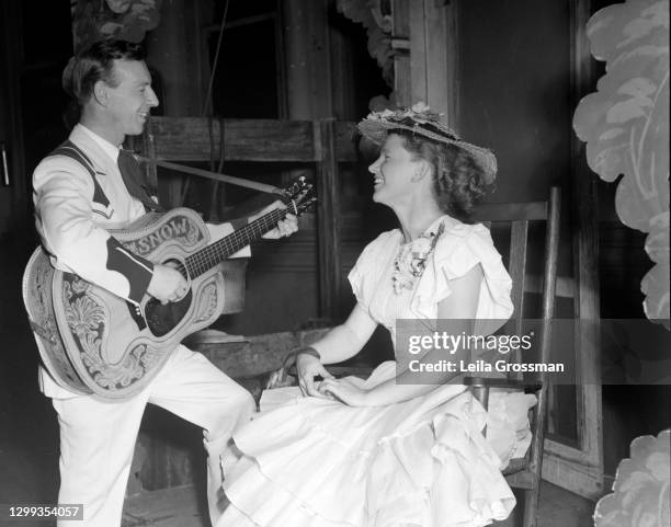 Country singer songwriter Hank Snow performs with Minnie Pearl on stage at the Grand Ole Opry in 1951 in Nashville, Tennessee.