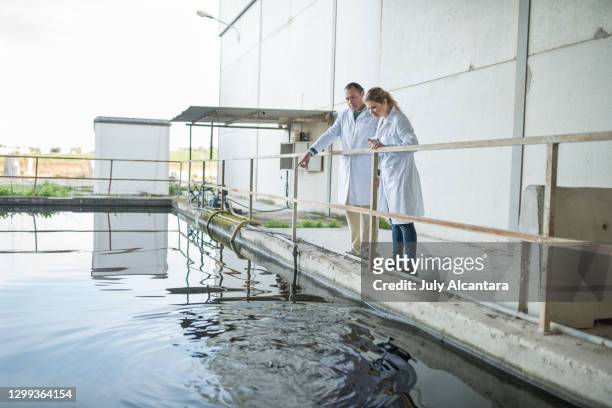 two chemical workers examine the industrial cooling pool of a construction company. - water tower storage tank stock pictures, royalty-free photos & images