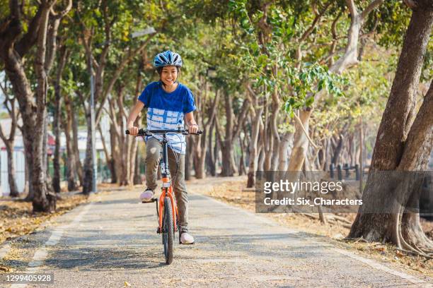 portrait of young asian girl enjoy riding a bicycle in the park outdoors - route 13 stock pictures, royalty-free photos & images