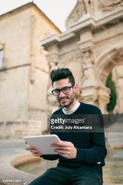 junger tourist mit tablet auf der plaza santa maria, baeza, spanien. lächelnd in die kamera - anzug ausland stock-fotos und bilder