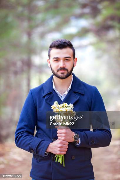 young man holding a bouquet of white narcissus on the background of forest. - man giving flowers stock pictures, royalty-free photos & images