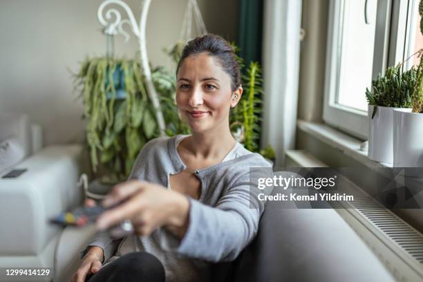 young adult woman with hearing aid watching television - hearing aids stock pictures, royalty-free photos & images