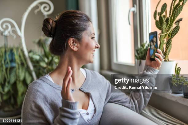 young adult woman with hearing aid having video conference. - hearing aid stock pictures, royalty-free photos & images