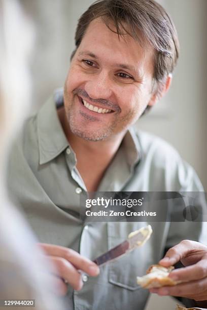 smiling man buttering bread - buttering stock pictures, royalty-free photos & images