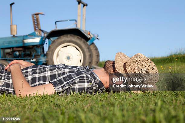man sleeping with hat over eyes in field - time out gesture stock pictures, royalty-free photos & images