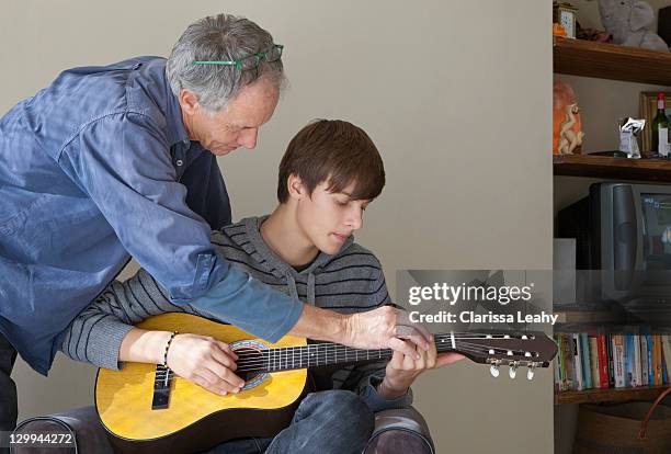 vater hilft sohn spielen sie gitarre - vater sohn musik stock-fotos und bilder