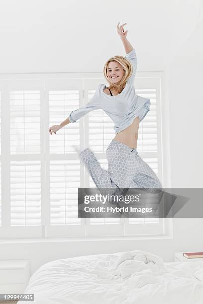 woman jumping on bed - jump on bed photos et images de collection