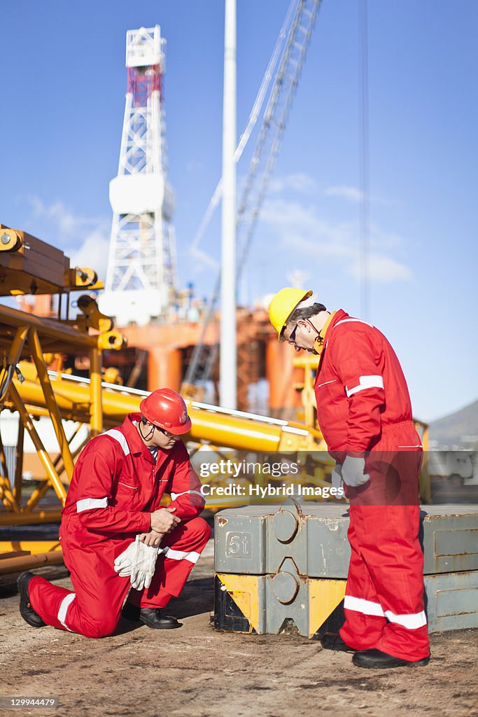 Workers on oil rig examining equipment