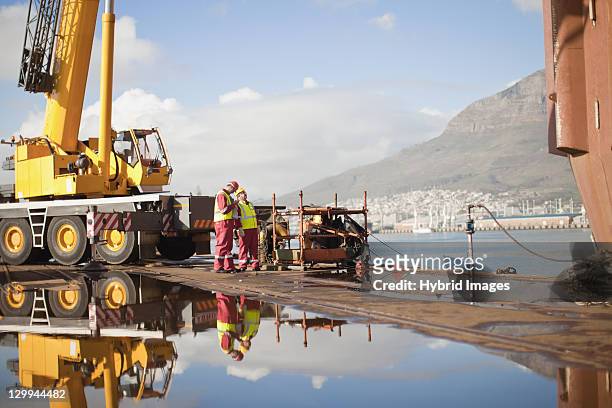 workers on oil rig standing by crane - oil rig engineers stock pictures, royalty-free photos & images