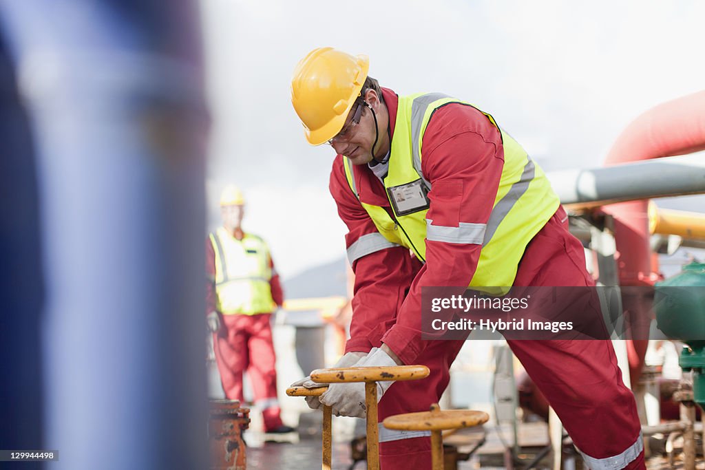 Worker turning wheel on oil rig