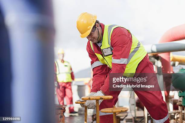 worker turning wheel on oil rig - horizontal drilling stock pictures, royalty-free photos & images