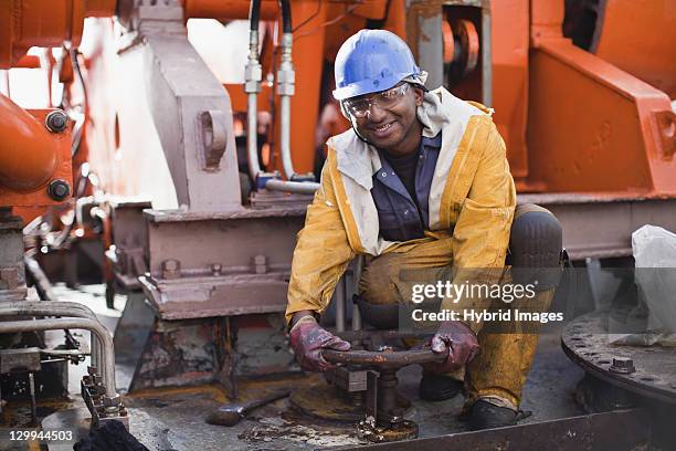 worker turning wheel on oil rig - oil well stock pictures, royalty-free photos & images