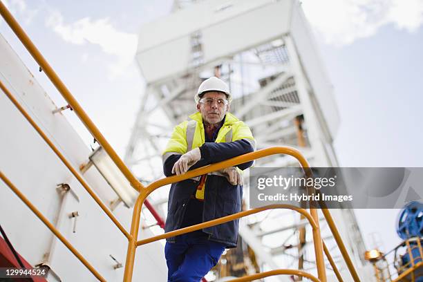 worker leaning on railing of oil rig - oljeplattform bildbanksfoton och bilder