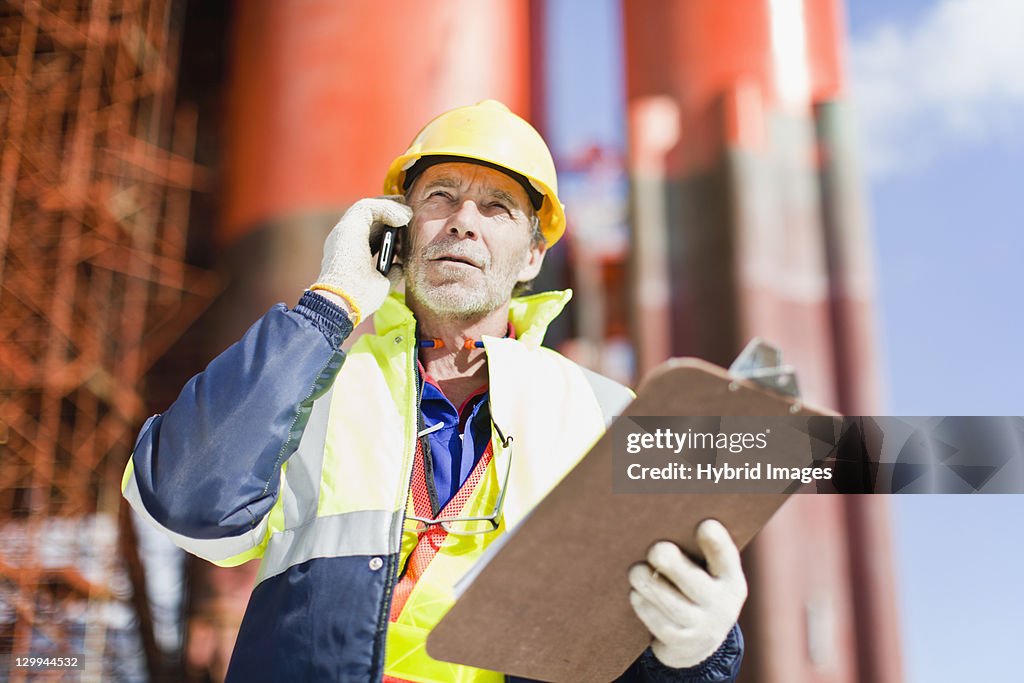 Worker talking on cell phone on oil rig