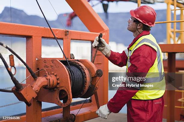 worker spooling cord on oil rig - olie industrie stockfoto's en -beelden