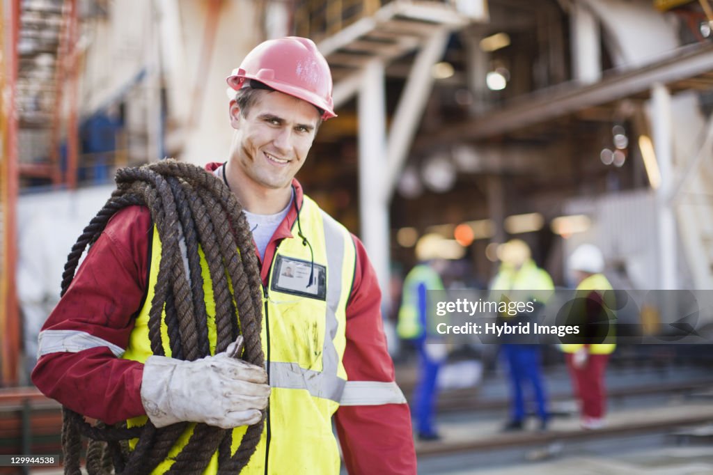 Worker carrying rope on oil rig