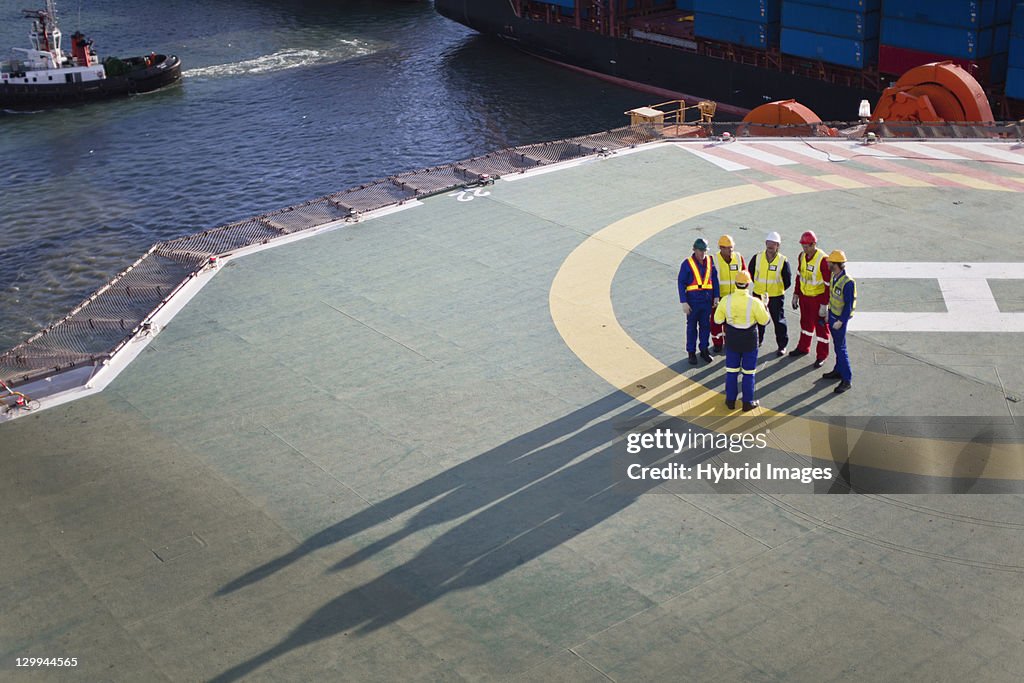 Workers talking on helipad of oil rig