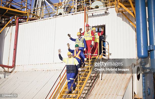 workers waving from steps of oil rig - oil rig portrait stock pictures, royalty-free photos & images